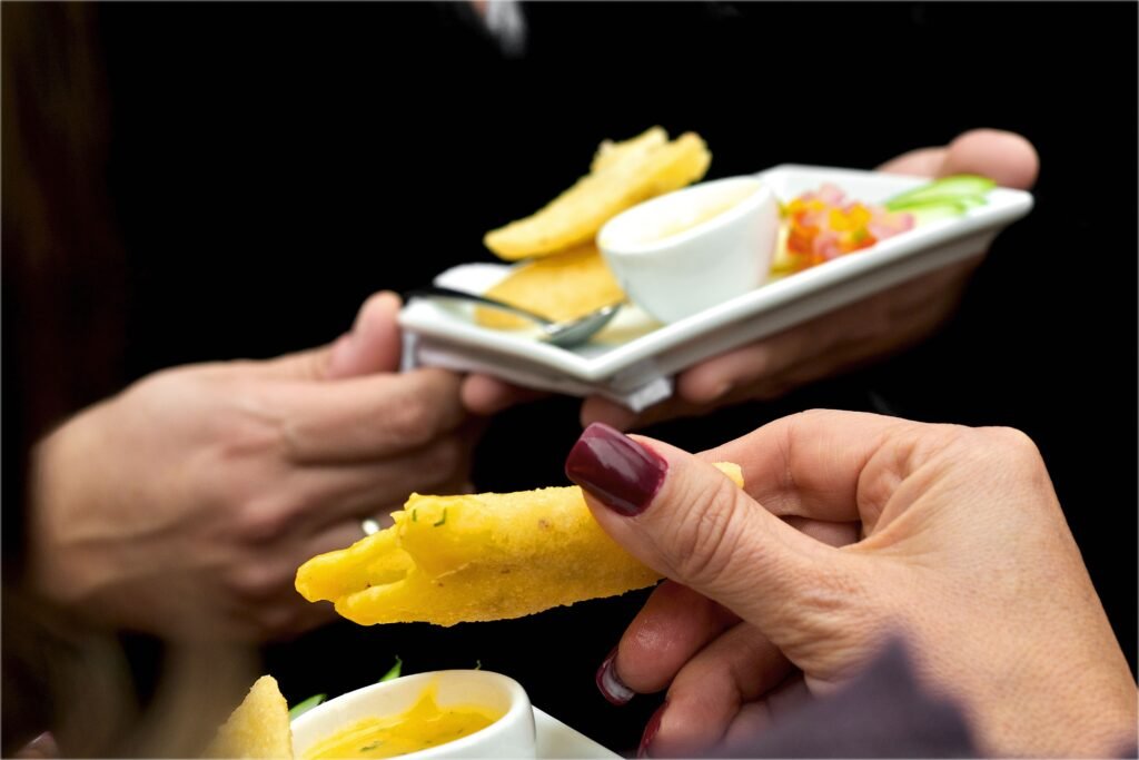 A close-up of party appetizers served on plates at a gathering, with dipping sauce.