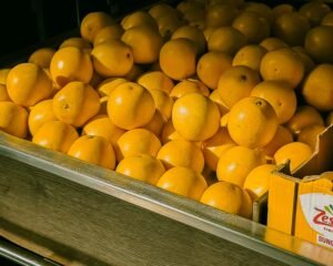 A colorful display of fresh oranges in a grocery store setting.